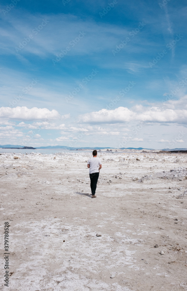 young man walks toward lake in white sand interesting landscape young man walks toward lake in white sand interesting landscape