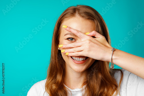 Happy young woman peeping through her fingers and smiling