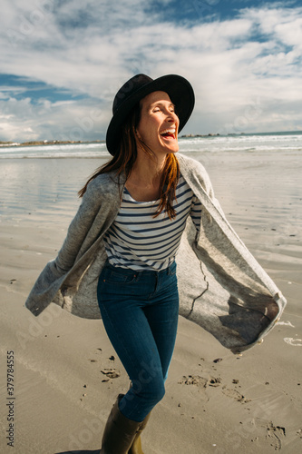 Beautiful young woman walking and playing on the beach wearing gumboots photo