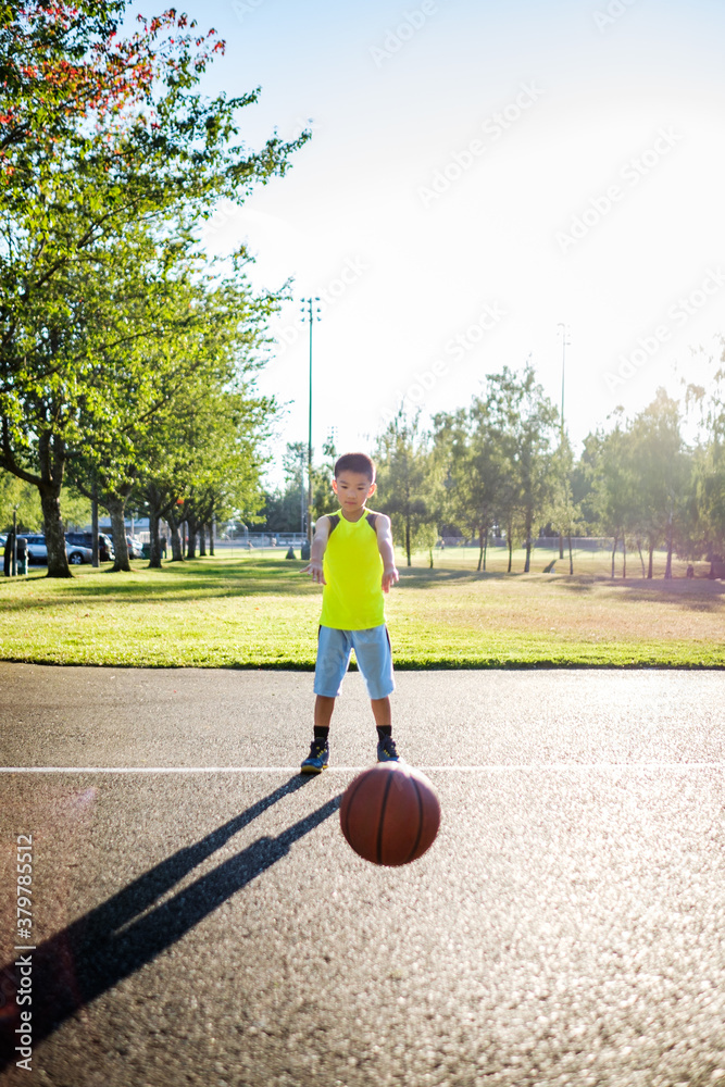 Asian kid passing a basketball in an outdoor basketball court Asian kid passing a basketball in an outdoor basketball court