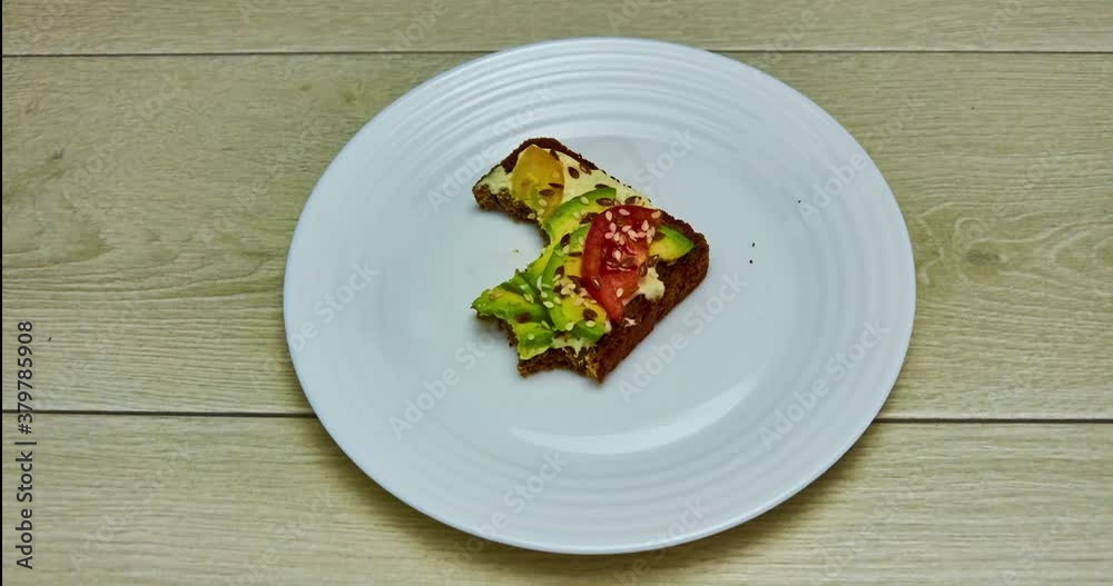 Stop motion animation of eating vegan food avocado toast bite by bite. Top view. Healthy eating concept Stop motion animation of eating vegan food avocado toast bite by bite. Top view. Healthy eating concept