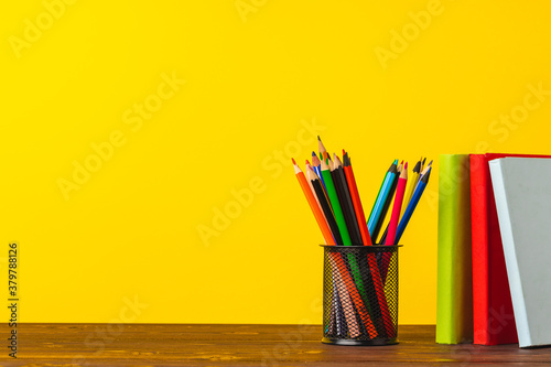 Cup of color pencils and stack of books