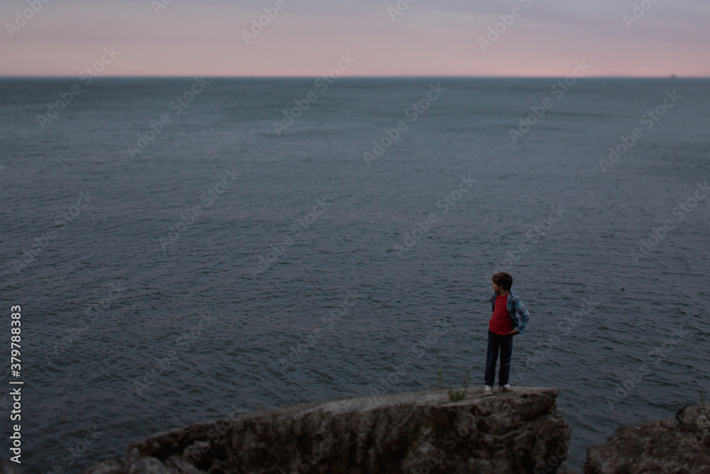 Young preteen caucasian boy outside in nature - standing on rock Young preteen caucasian boy outside in nature - standing on rock