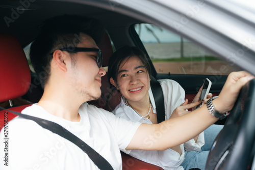Couple traveler sit inside a car using map application on smartphone.
