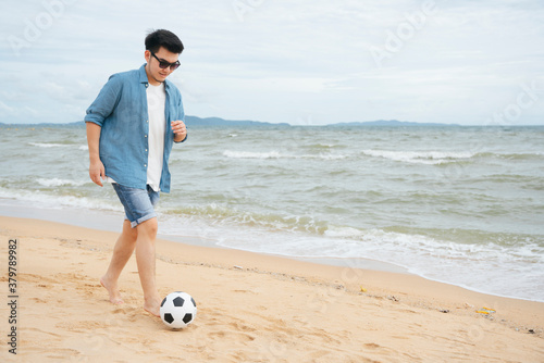 Athelete man playing soccer or football on the beach. photo