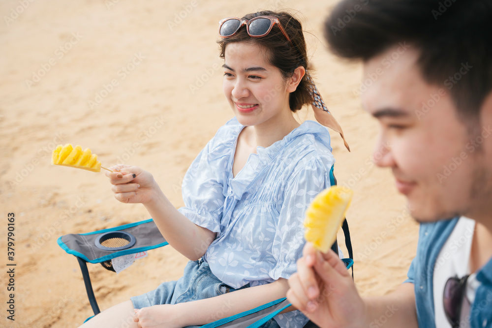 Asian young traveler woman enjoy eating pineapple with boyfriend on the beach. Asian young traveler woman enjoy eating pineapple with boyfriend on the beach.