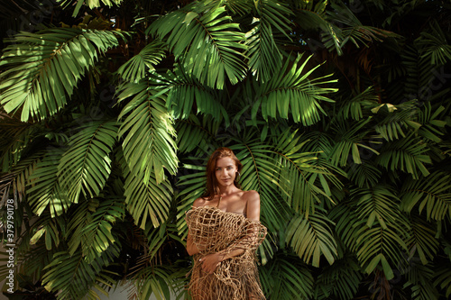 Young attrative brnette model poses against a background of greenery on a tropical island photo