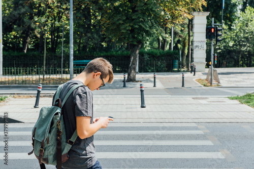 Teenager playing location-based augmented reality game on his smartphone not paying attention to the traffic photo