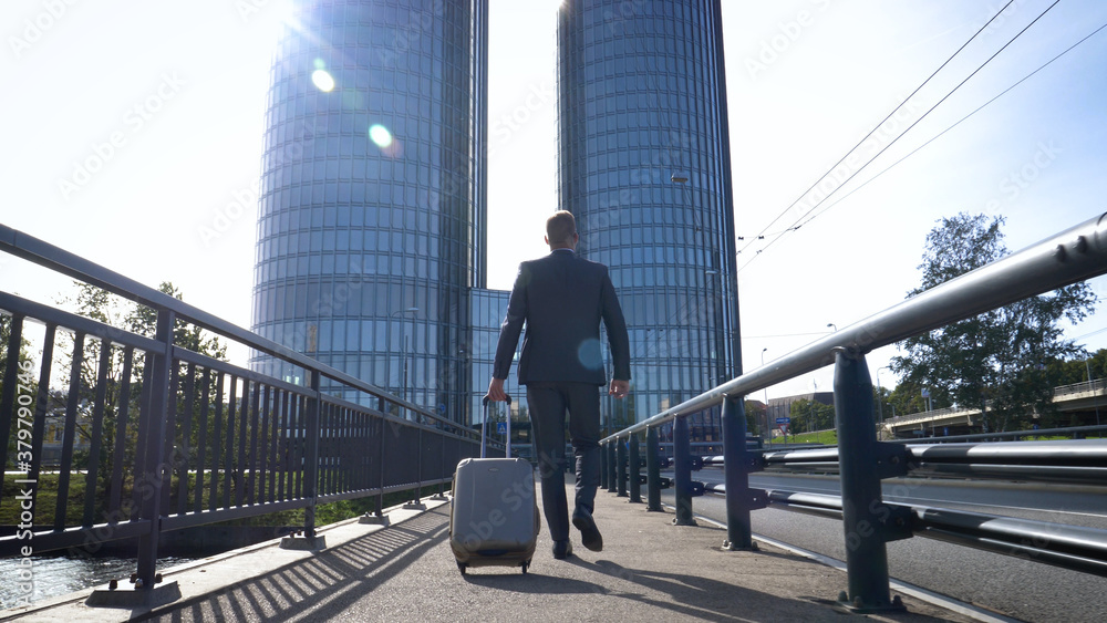 Businessman with baggage on the go. Caucasian businessman rolling luggage in lobby. Businessman with baggage on the go. Caucasian businessman rolling luggage in lobby.