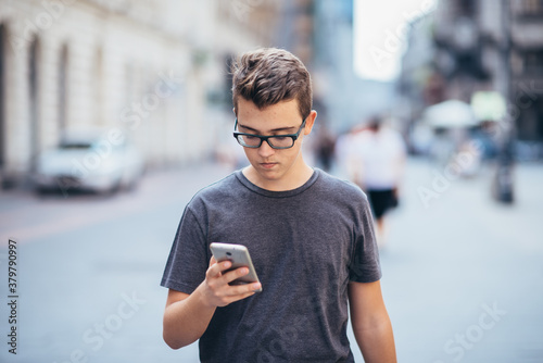 Teenager playing location-based augmented reality game on his smartphone in the city photo