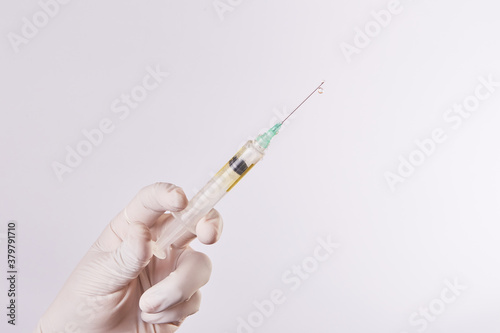 Mano de hombre con guantes sostiene una Inyección con vacuna en fondo aislado. 