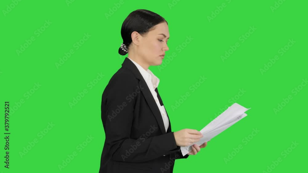 Serious Businesswoman reading report preparing for a presentation while walking on a Green Screen, Chroma Key. Serious Businesswoman reading report preparing for a presentation while walking on a Green Screen, Chroma Key.