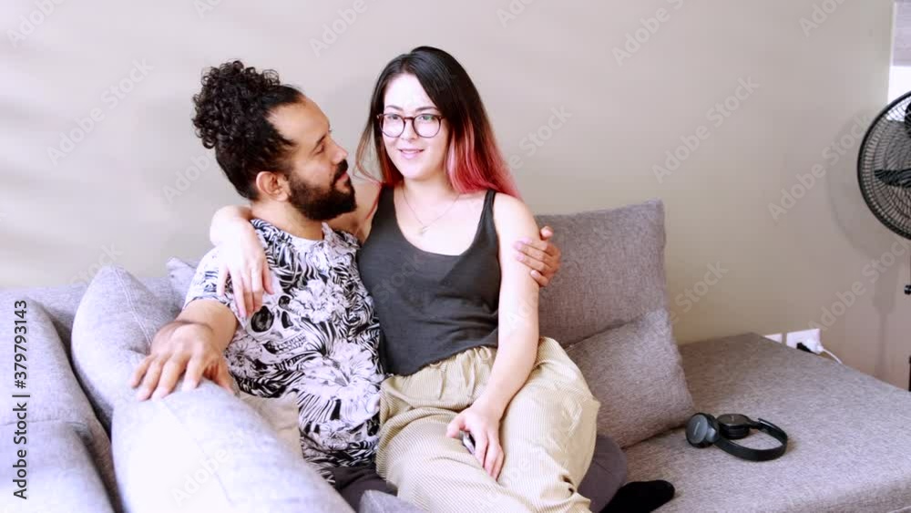 pareja mexicana pasan tiempo juntos en sillon dentro de casa utilizando un telefono inteligente