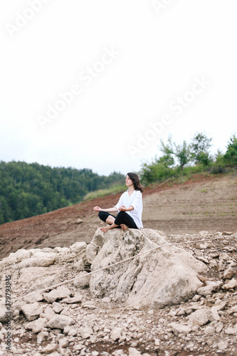 Woman meditating, sitting on the rock photo