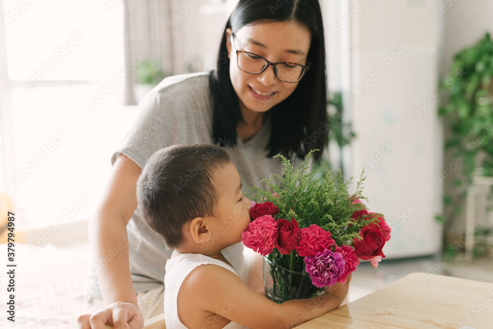 Cute toddler boy holding flowers with his mother Cute toddler boy holding flowers with his mother