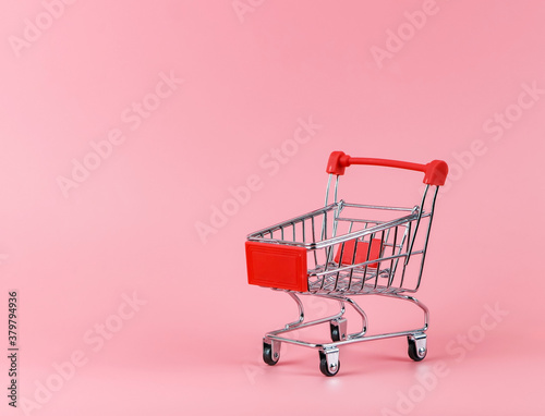empty shopping cart on pink background with copy space.