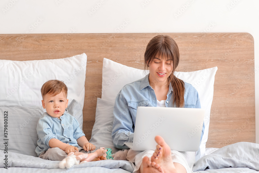 Working mother with little son in bedroom at home
