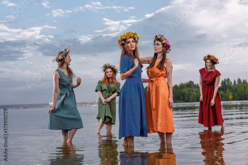 Lovely girls in flower wreaths in nature. Ancient pagan origin celebration concept. Summer solstice day. Mid summer. Ancient rituals.