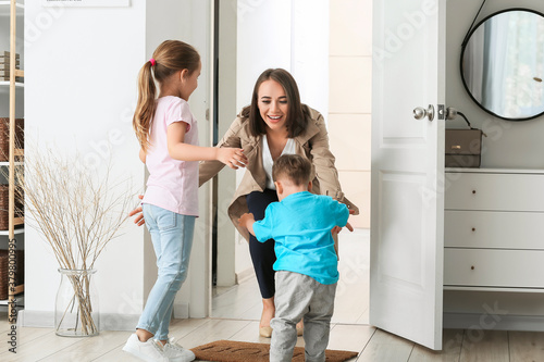 Happy children meeting their mother after work at home