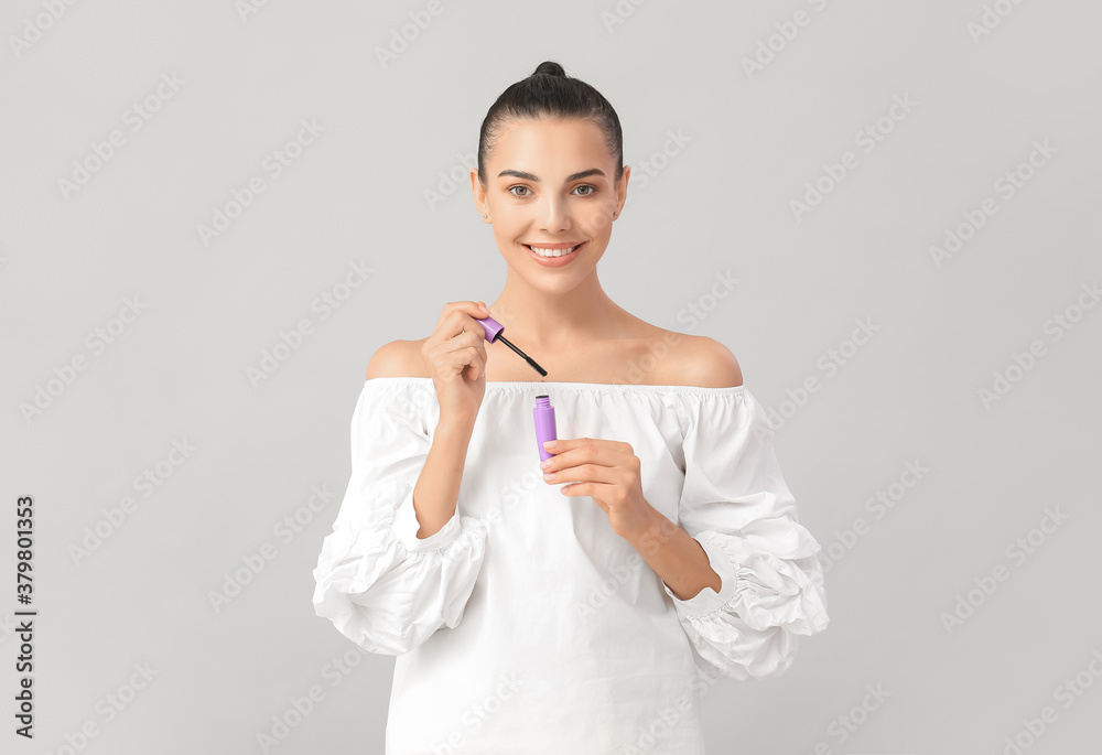 Beautiful young woman with mascara against light background Beautiful young woman with mascara against light background