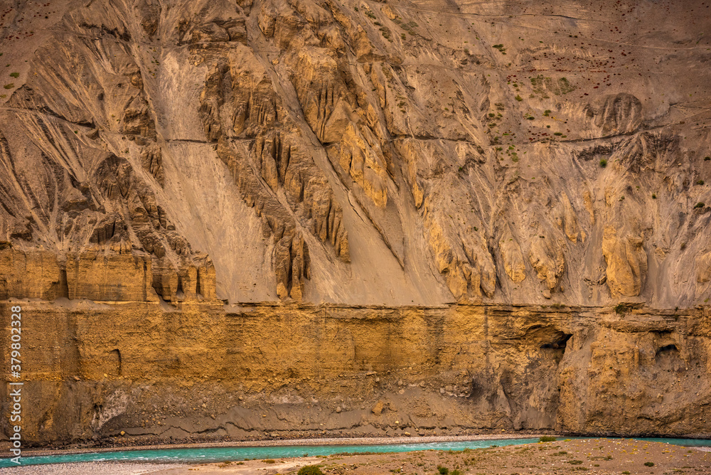 Gully erosion landscape prominent in cold desert of Spiti due to barren steep slopes & weak unconsolidated geological mud rocks. River erosion also visible on downward slopes of hills. - obrazy, fototapety, plakaty 