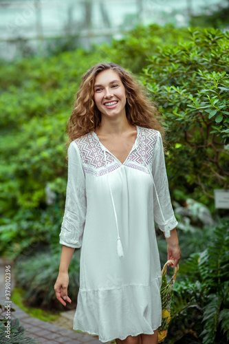 Smiling woman in white dress in greenhouse