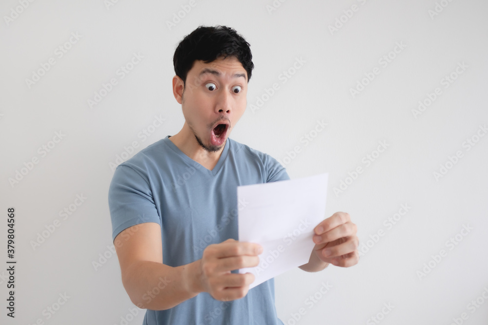 Asian man surprise and shocked by the letter in his hand on isolated background. Asian man surprise and shocked by the letter in his hand on isolated background.