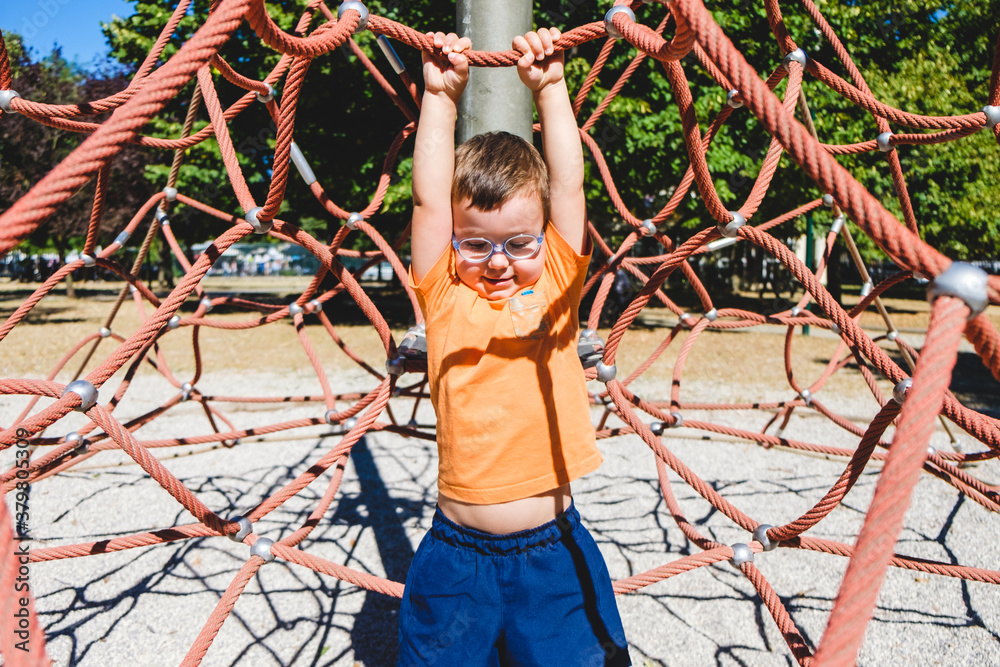 Happy Male Toddler Climbing a Net at the Playground Happy Male Toddler Climbing a Net at the Playground