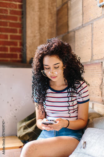 A young hispanic woman looking down at her phone in a cafe