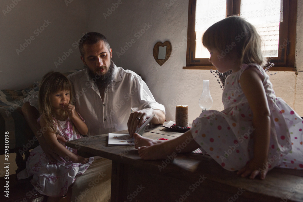 Father reading a book to his little two daughters at home Father reading a book to his little two daughters at home