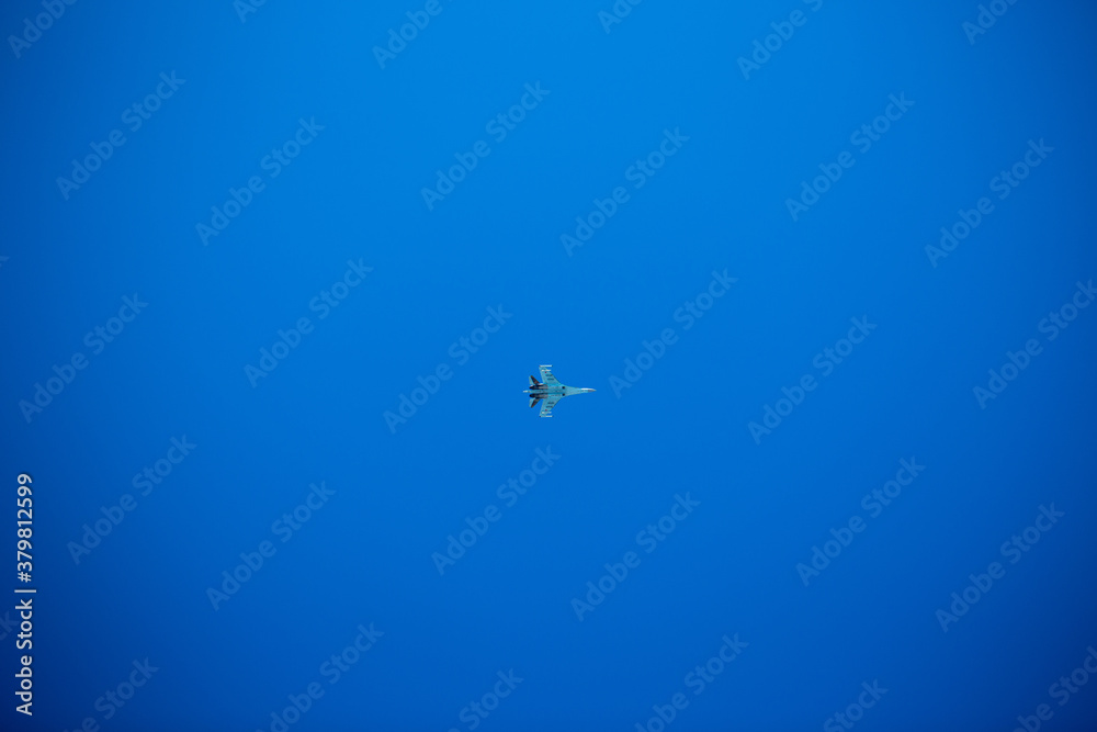 Fototapeta premium A military blue plane flies against the background of a clear blue sky.