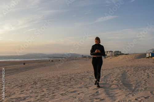 Beautiful caucasian woman walking along the beach at Costa da Caparica near Lisbon city center. Beautiful young woman with leather jacket relaxing on the beach at sunset in Caparica. Portugal, 2020