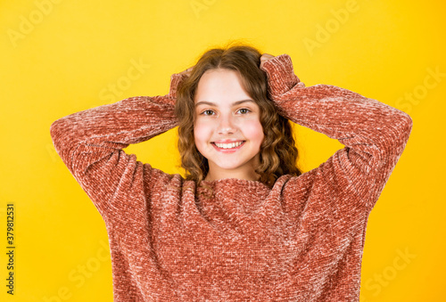 Enjoy silky hair. Beautiful little model. Healthy curls. Easy hairdo. Hairdresser salon. Adorable small child. Beauty supplies. Perfectly untangle curly hair. Pretty girl curly hair yellow background © be free