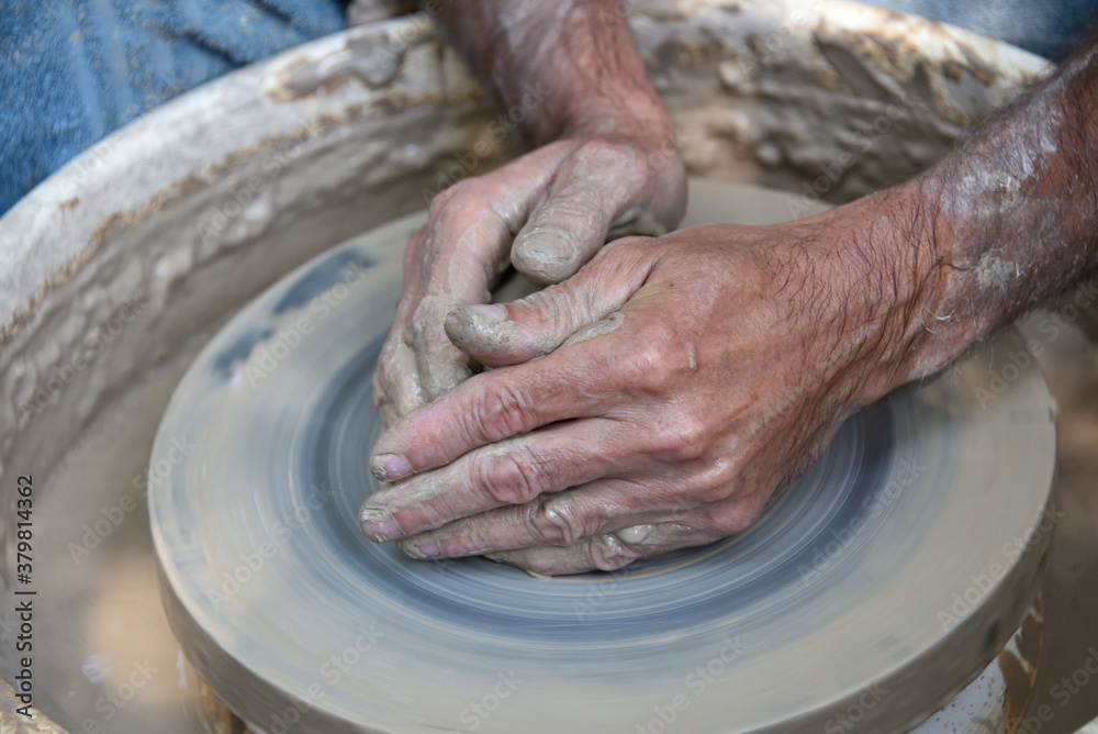 Master potter using a potter's wheel creates a vase from clay