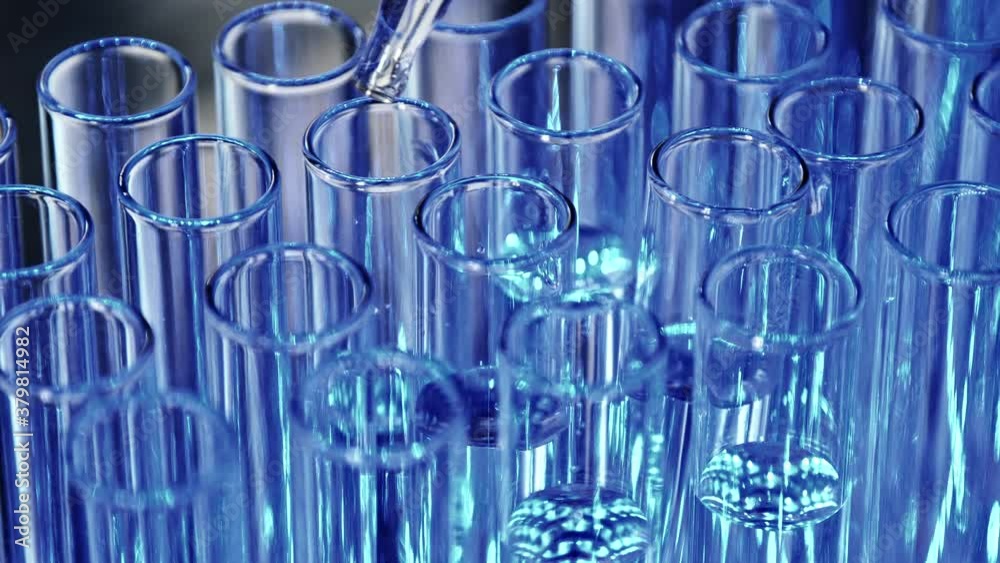 The tubes, illuminated with blue light, are filled with liquid from the pipette tip.