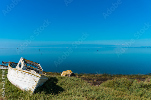 Abandoned boat remains on a beach looking out to the mediterranean ocean. Relaxing background screensaver. Save the planet concept. Save the oceans. Wooden pier. Mirror water limitless. photo
