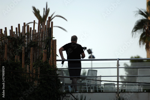 A man is leaning against a railing while taking a selfie.