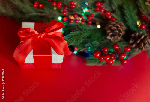 A gift box with a red ribbon and a spruce branch on a red background. Concept sales  discounts  Christmas holidays and shopping. Christmas card. copy spase