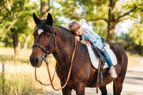 Cute little girl with long hair riding a horse outdoors. Pet therapy © sushytska