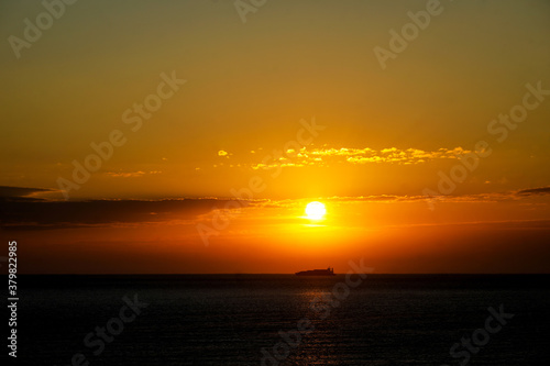 Sun rises over the Black Sea while a big cargo boat is passing by. © MoiraM