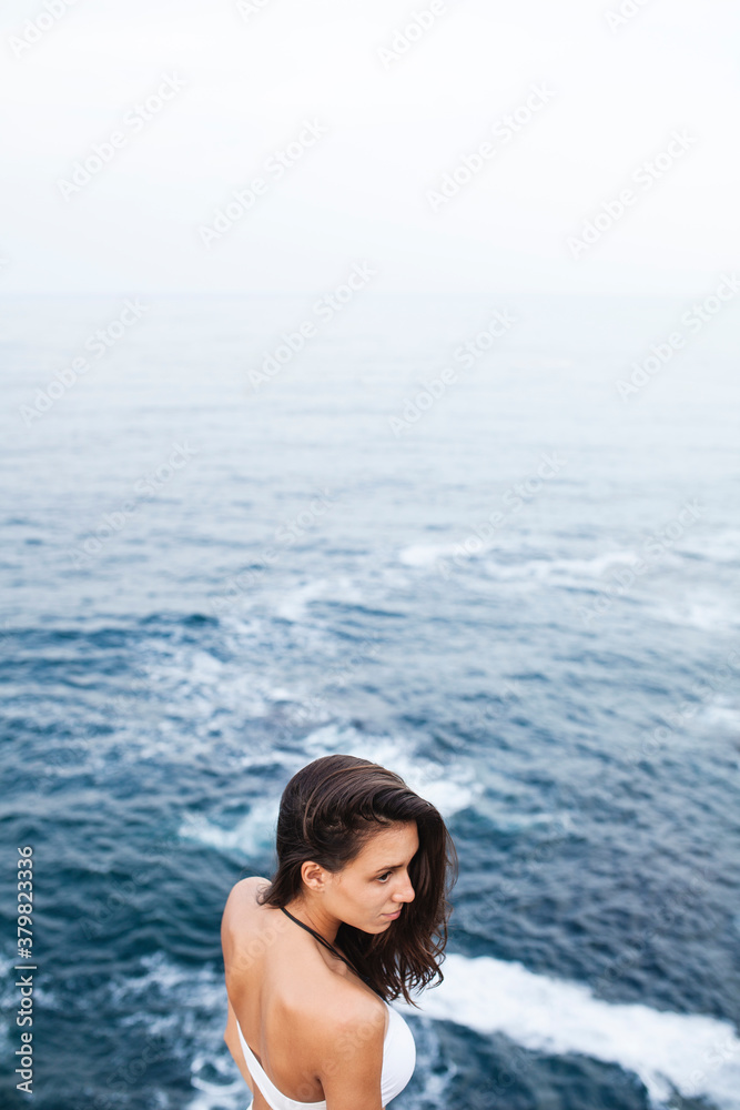 Beautiful woman standing on the edge of a cliff at the seashore