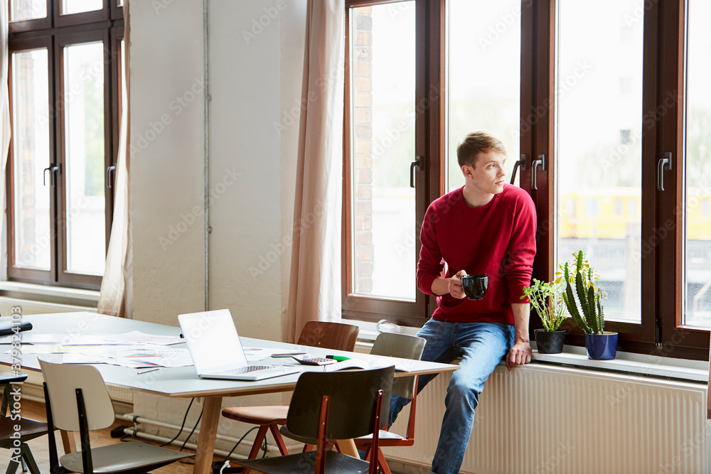Businessman Having Coffee While Looking Through Window Businessman Having Coffee While Looking Through Window