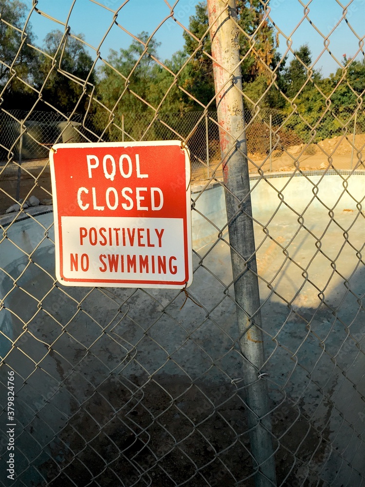 Sign Saying Pool Is Closed - Positively No Swimming Next To An Empty 