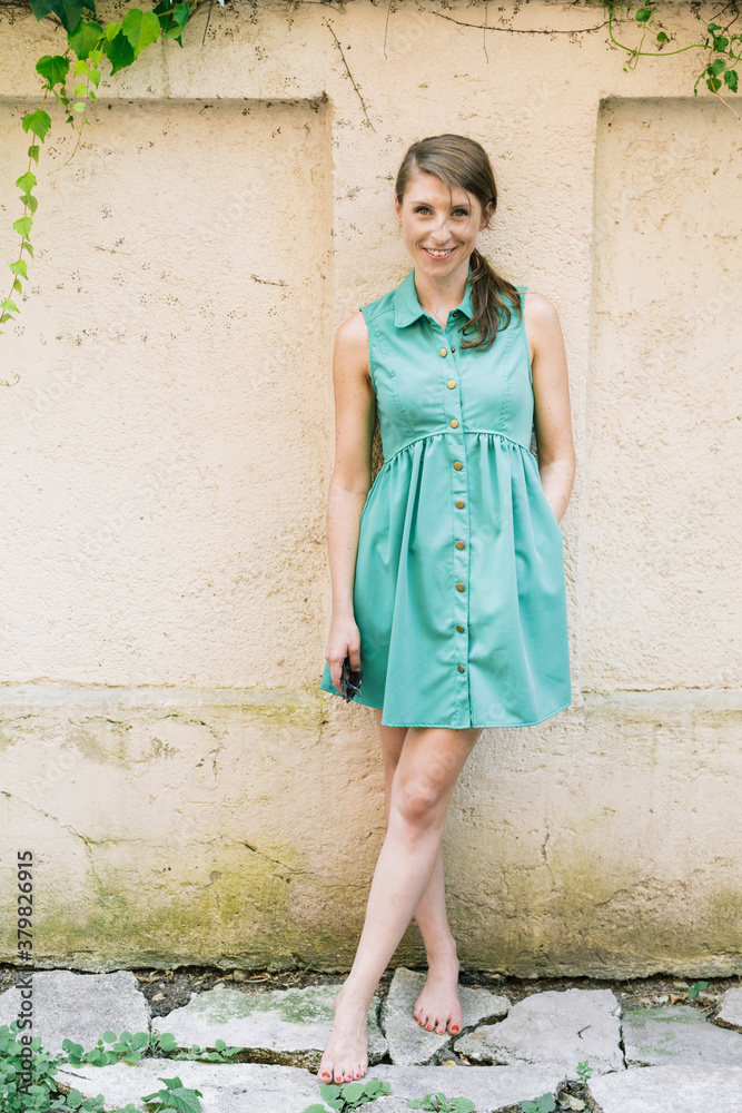 Young woman leaning against a wall in a backyard Young woman leaning against a wall in a backyard