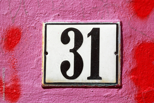Weisses Hausnummernschild Nr. 31 auf rot bemalter Hauswand, Deutschland, Europa photo