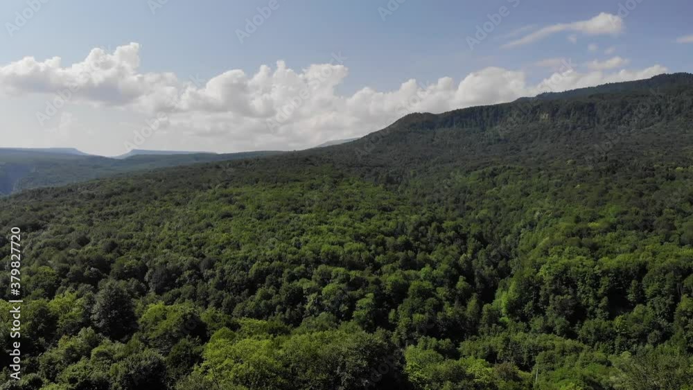 Aerial view of flight over valley and hills covered with deciduous forest in summer sunny day Aerial view of flight over valley and hills covered with deciduous forest in summer sunny day
