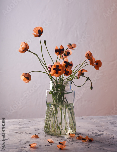 A Little Red Poppies Bouquet Arranged In Classical Style Stillife of popies in a glasses vase photo