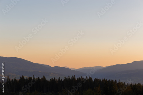 Landscape with mountains at sunset. Orange Sun setting behind the Mountains. Colorful sunrise over the Carpathian Mountains.