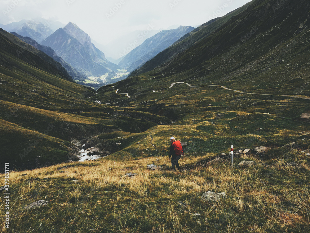 Lonely Hiker Walking Downhill in Swiss Alpine Landscape Lonely Hiker Walking Downhill in Swiss Alpine Landscape