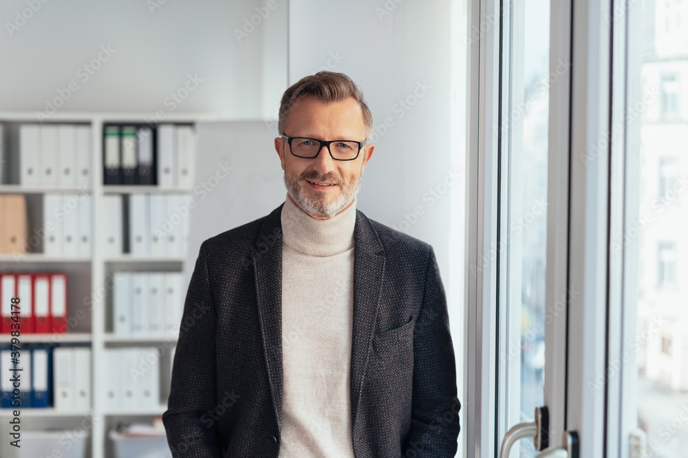 Attractive smart businessman standing in an office Attractive smart businessman standing in an office
